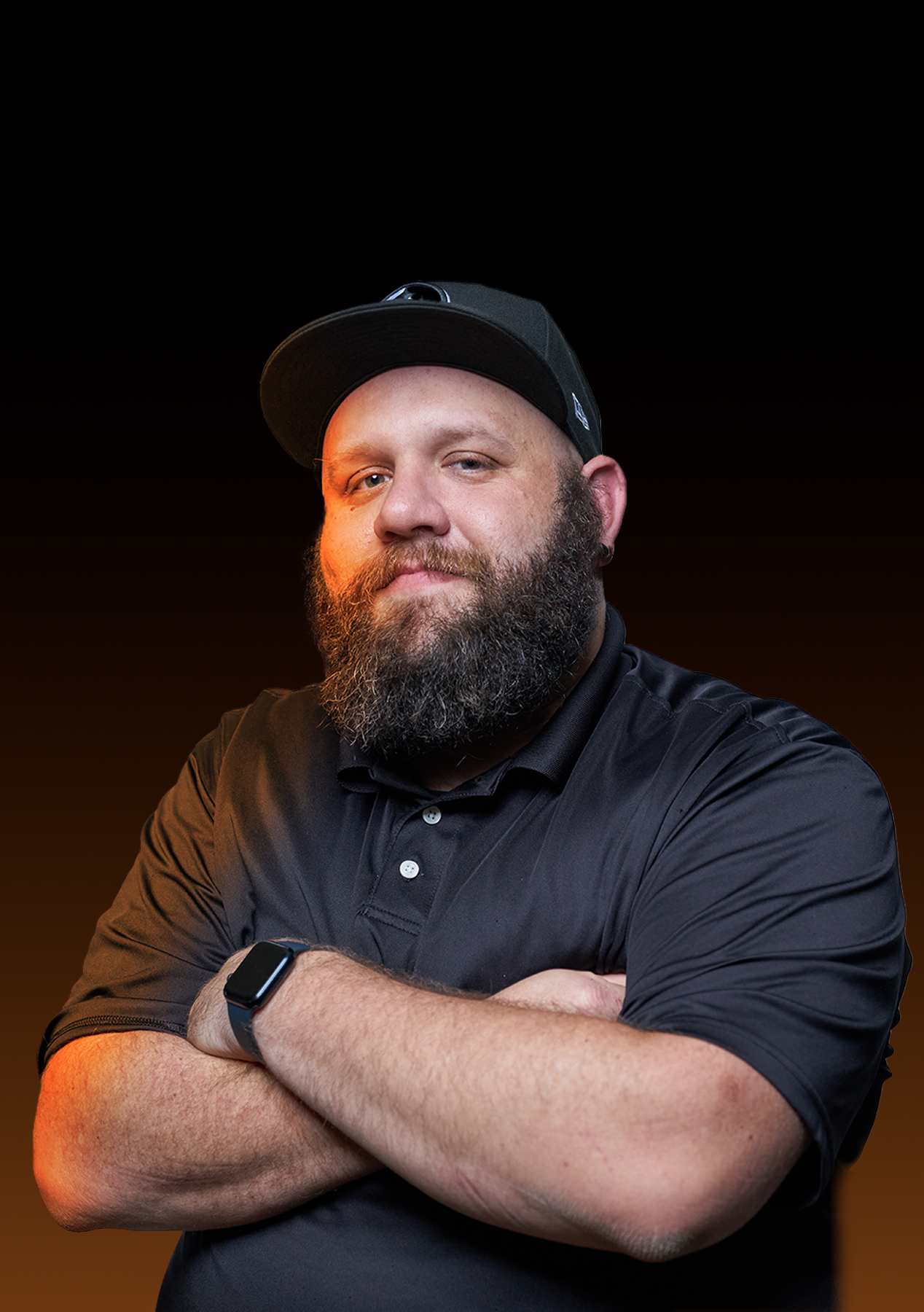 Steve Dirks wearing a black cap and polo, with warm orange portrait lighting